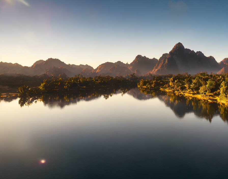 Scenic lake with mountain range and forest under clear sky