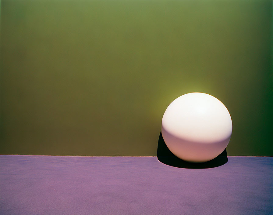 Minimalist scene: Glowing orb on purple floor, green wall - tranquil, modern ambiance