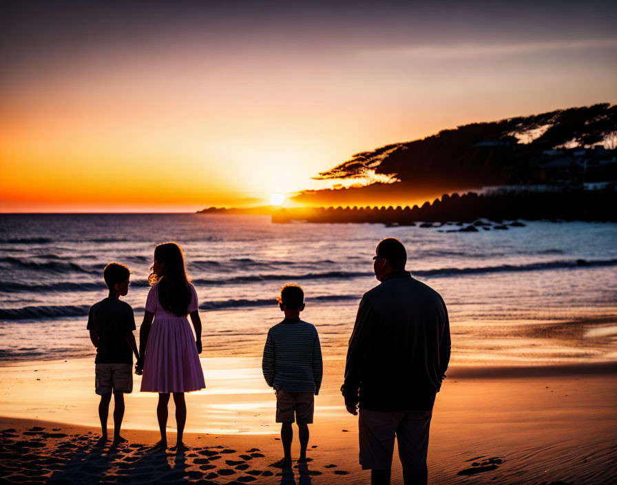 Family of Four Silhouettes on Beach at Sunset