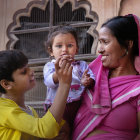 Three women in traditional Indian attire with intricate jewelry in a vibrant market.