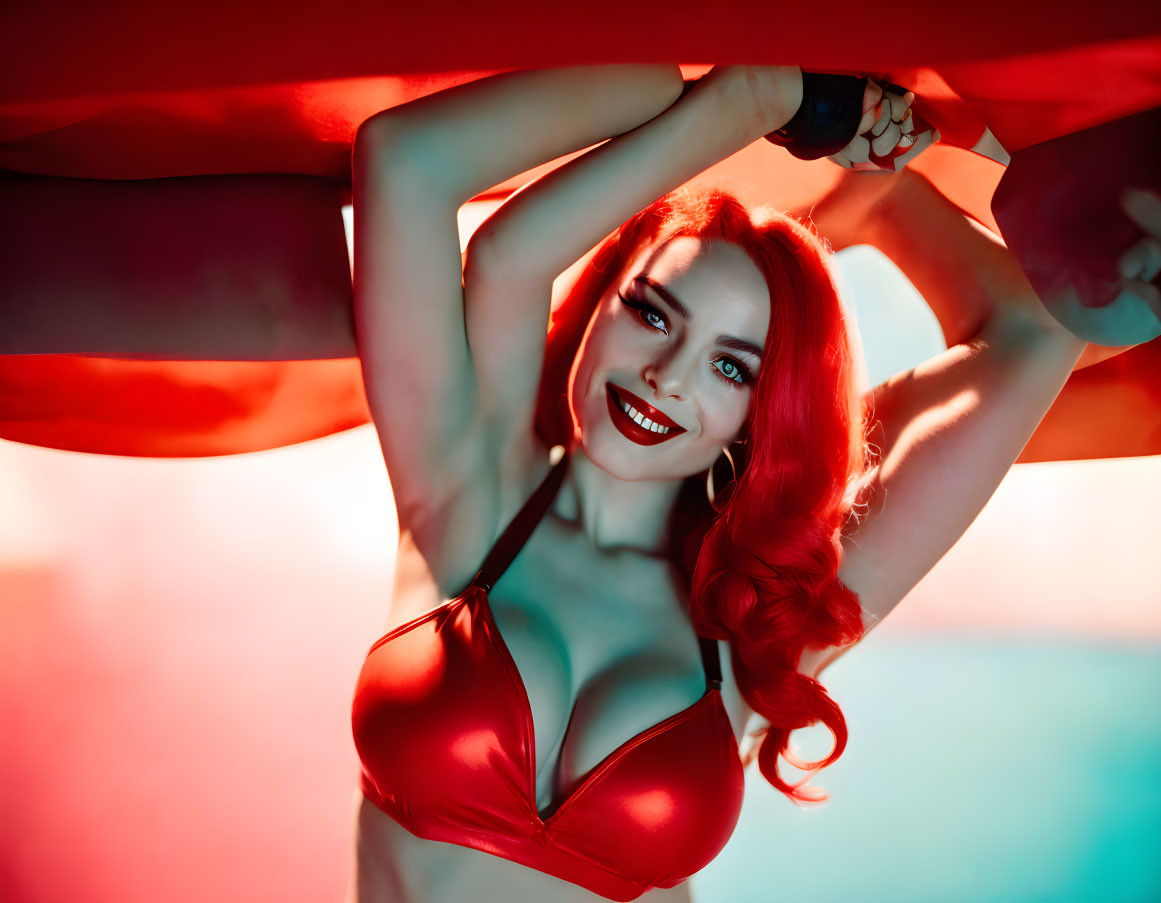 Red-haired woman posing confidently with fabric under dramatic red and blue lighting