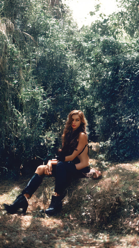 Woman in black outfit sitting among trees with long hair cascading down