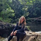 Woman in black outfit sitting among trees with long hair cascading down