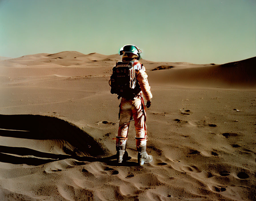 Astronaut with box-like instrument on Mars-like desert.