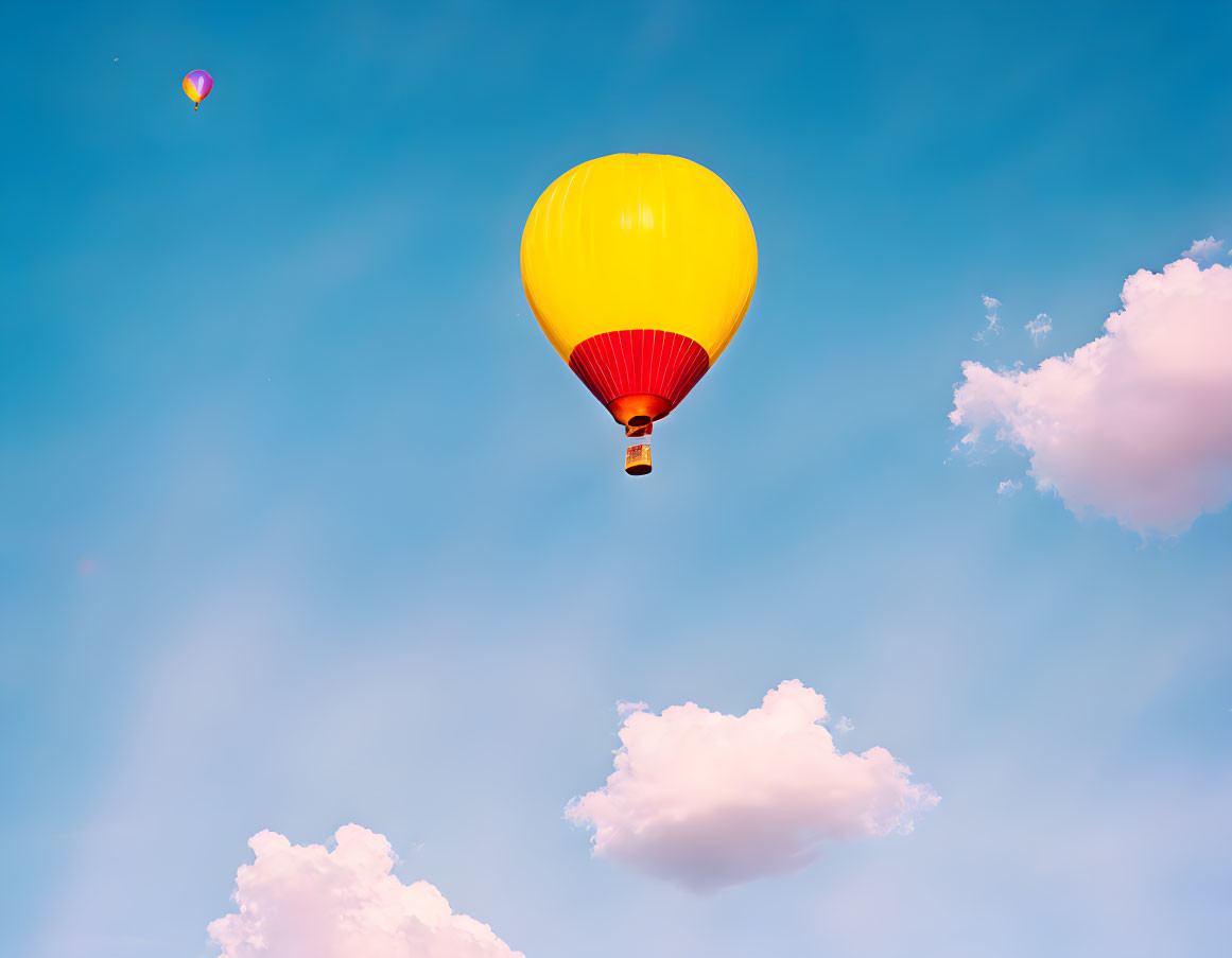 Colorful hot air balloon in blue sky with clouds and smaller balloon