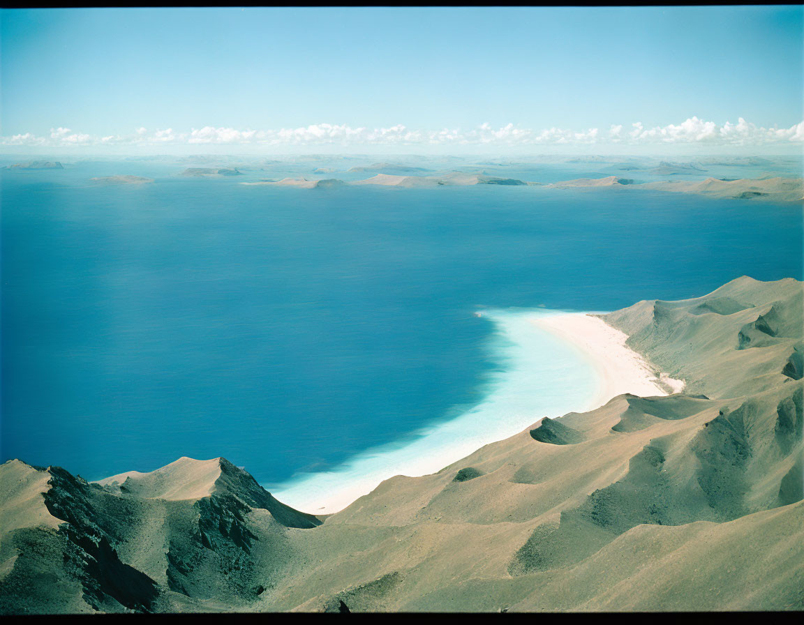 Scenic blue lake with sandy shores and rolling hills