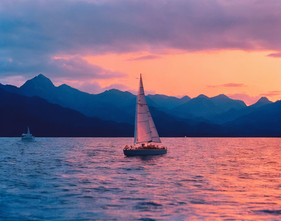 Sailboat on tranquil waters at sunset with pink-and-orange skies