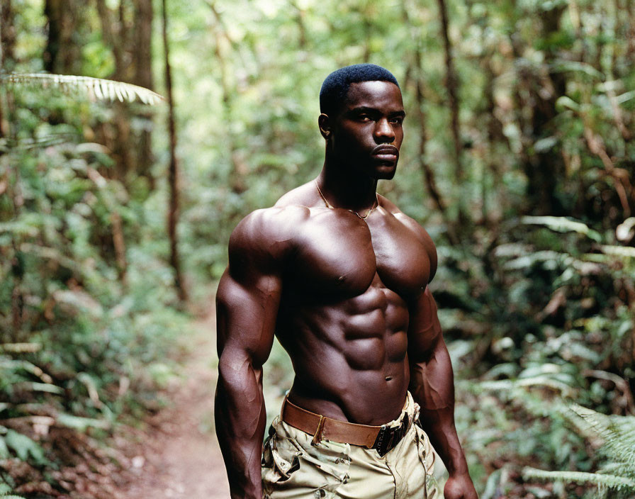 Muscular man in forest surrounded by lush greenery