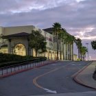 Mediterranean-style building at twilight with palm trees and dramatic sky