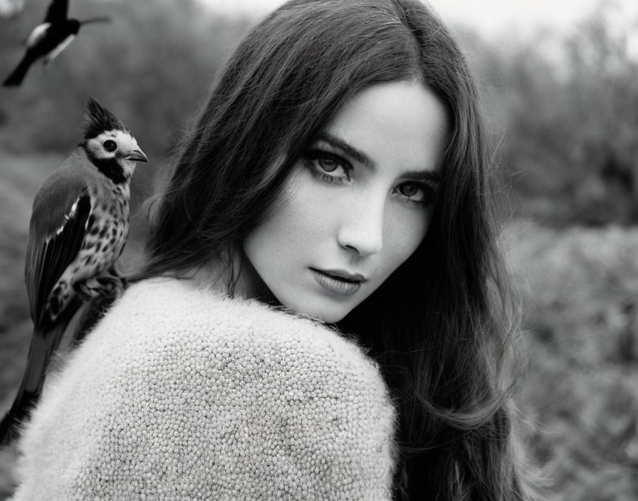 Monochrome image of woman with dark hair and intense eyes, bird on shoulder