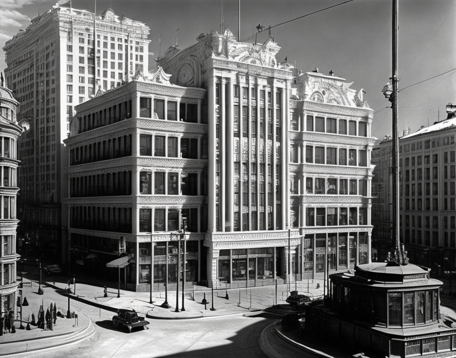 Vintage black and white photo of street corner with classical architecture, tram, and vintage cars.