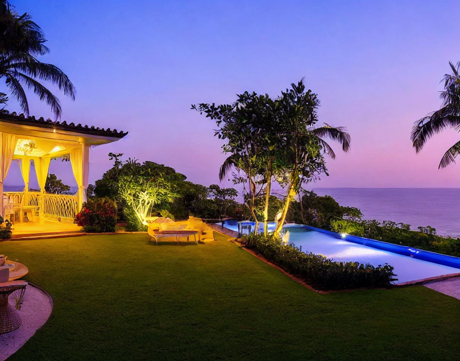 Tranquil coastal backyard with illuminated pool and ocean view