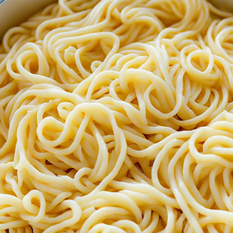 Cooked yellow noodles with soft texture and glossy sheen close-up.