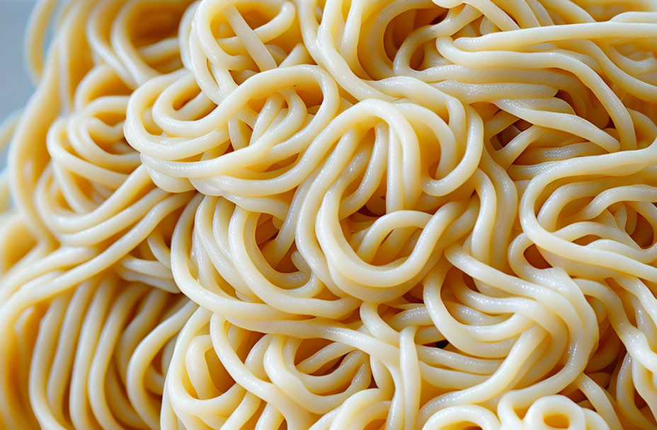 Yellow cooked spaghetti noodles intertwined on a plate