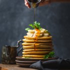 Colorful Pancakes with Syrup, Berries, Mint, and Cream on Dark Background