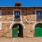 Vibrant Mediterranean-style building with green doors and colorful flowers