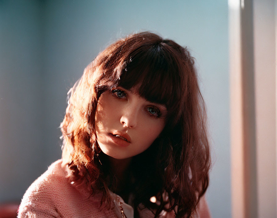 Woman with Bangs and Wavy Hair in Pink Top under Sunlight Shadows