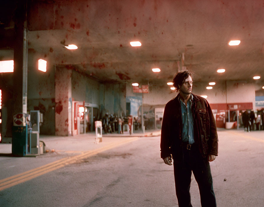 Man in leather jacket in dimly lit urban underpass with peeling paint