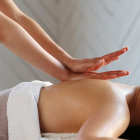 Hands applying pressure on bare back during back massage.