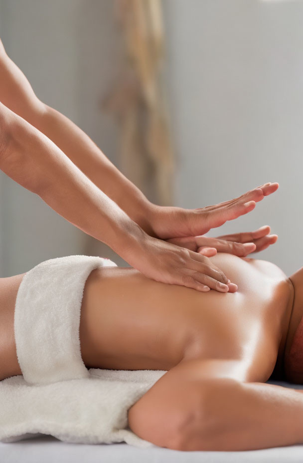 Hands applying pressure on bare back during back massage.