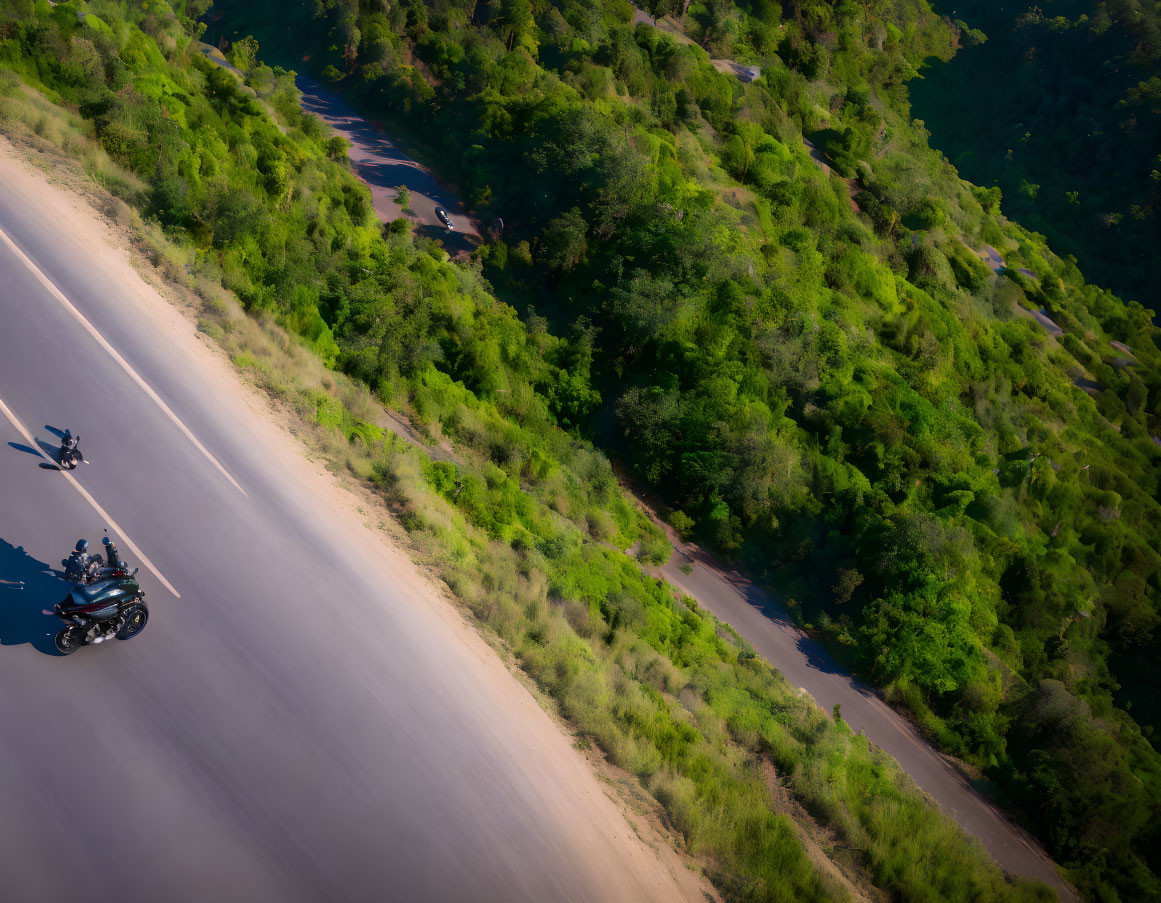 Curved road with motorcycle and rider in lush greenery