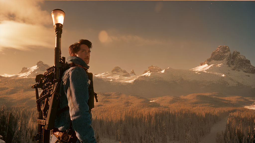 Person admiring snow-capped mountains at sunset next to streetlamp