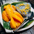 Colorful Papaya and Purple Rice Plate with Yellow Flowers on Banana Leaf