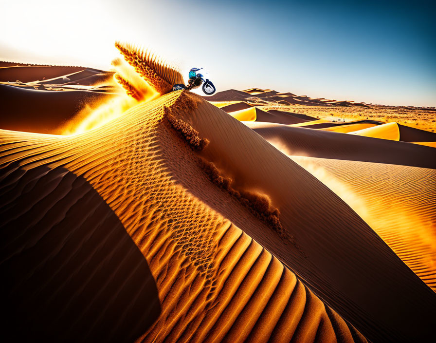 Motorcyclist riding on sand dune under clear sky