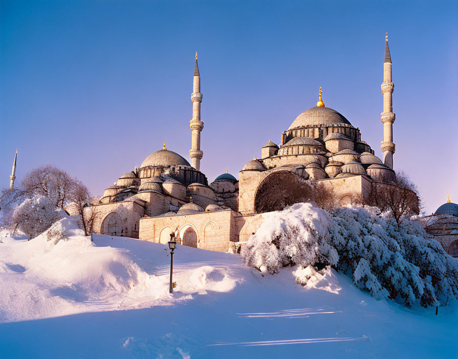 Historic mosque with domes and minarets in snowy landscape