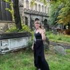 Woman in Black Dress on Futuristic Greenhouse Bridge with Lush Greenery