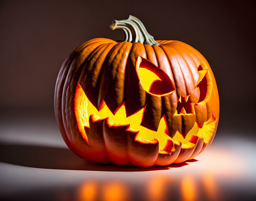 Menacing face carved pumpkin glowing on dark background