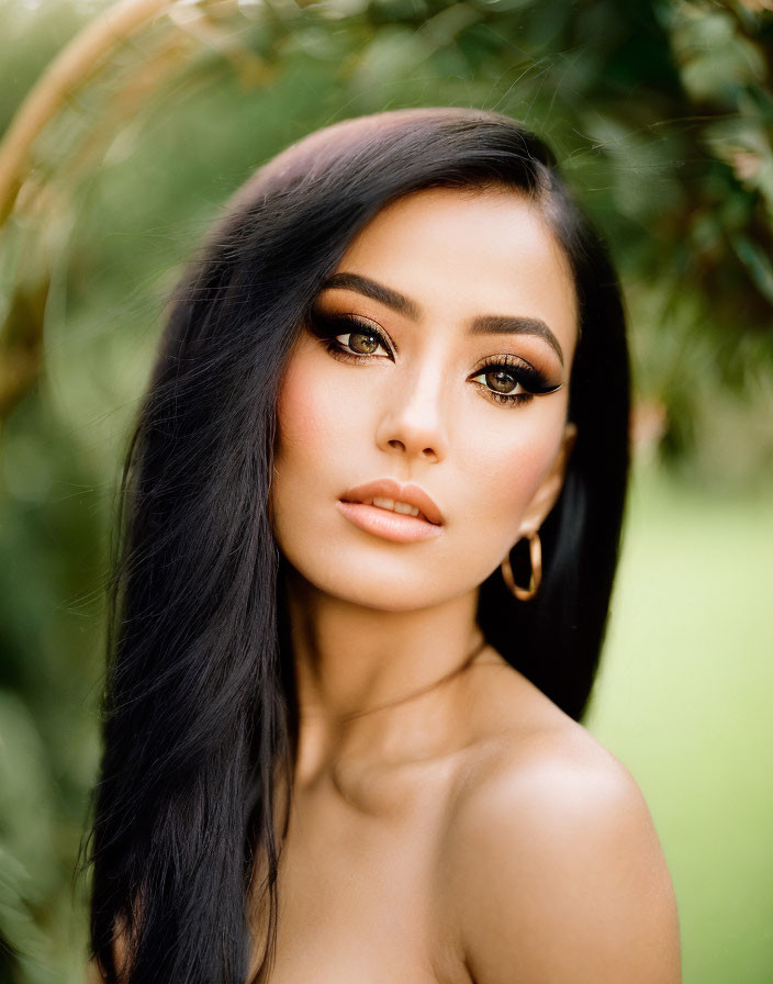 Portrait of a person with long dark hair and eyeliner on blurred green background