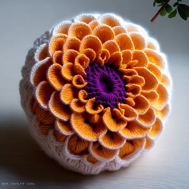 Handmade crochet orange flower with deep purple center on minimalistic background