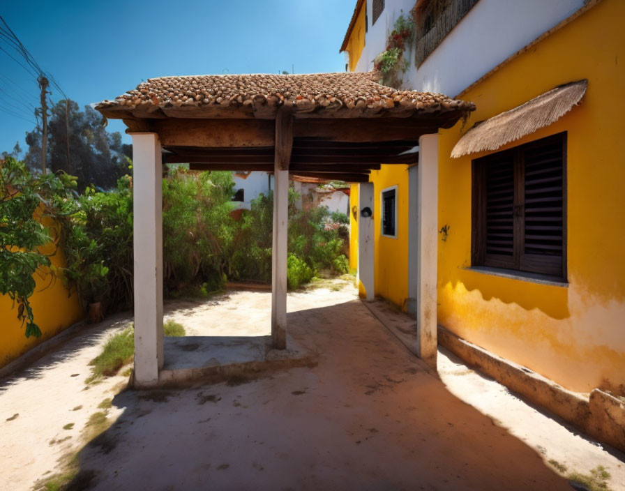 Rustic courtyard with yellow walls, tiled roof pergola, wooden beams, greenery, and