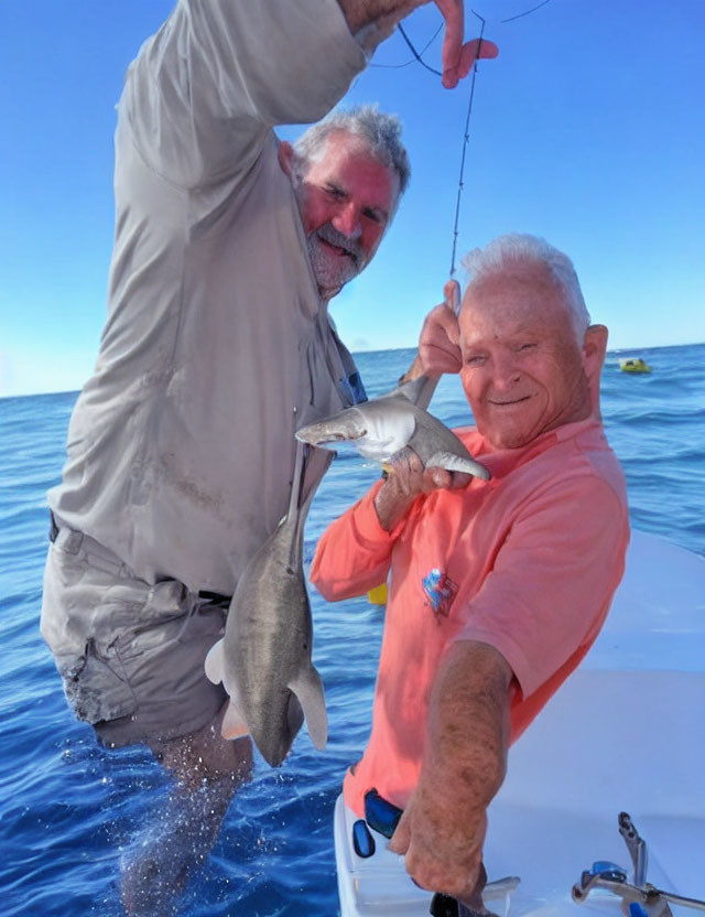 Men on boat with caught shark in blue ocean