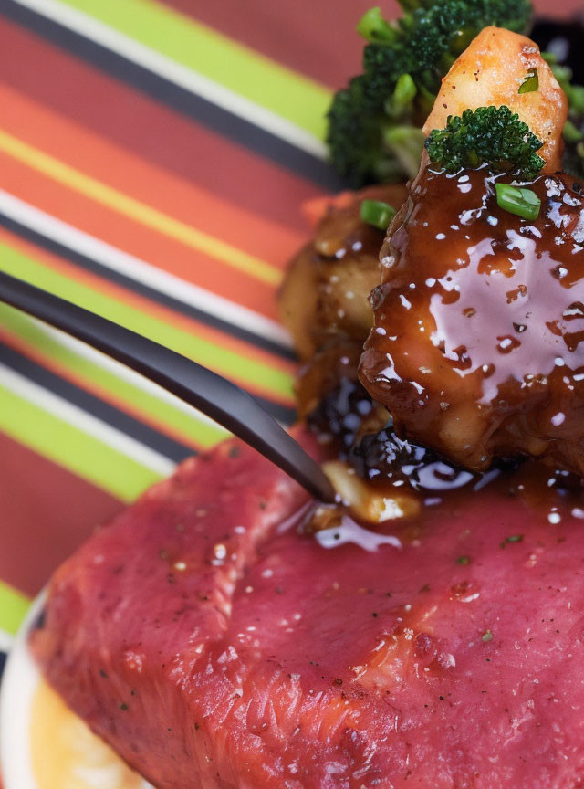 Medium-rare steak with broccoli, chicken skewer, sesame seeds, and glaze.