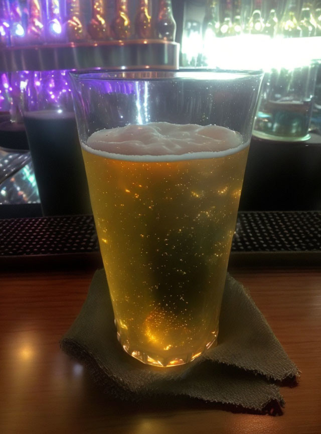 Frothy beer glass on bar napkin with purple accent lights