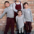 Family of Five in Cozy Winter Clothing Smiling Against Brick Wall