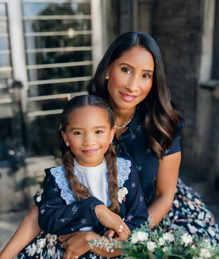 Smiling woman and girl in matching blue star-patterned dresses sitting happily