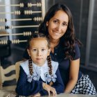 Smiling woman and girl in matching blue star-patterned dresses sitting happily