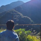 Sunlit scene with blue sky, fenced road, green mountains, and lens flare.