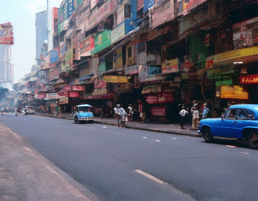 Vibrant urban scene with colorful shops, pedestrians, and vintage cars.