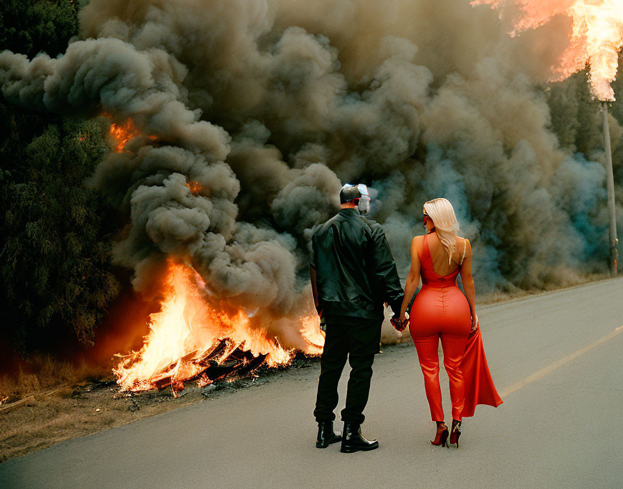 Couple walking away from raging wildfire near road