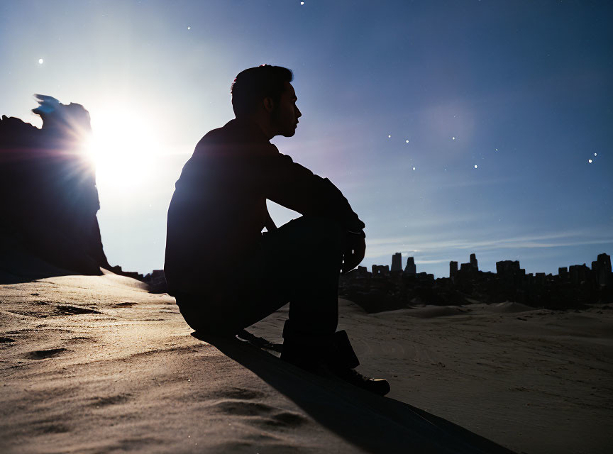 City skyline silhouette at sunset with person sitting.