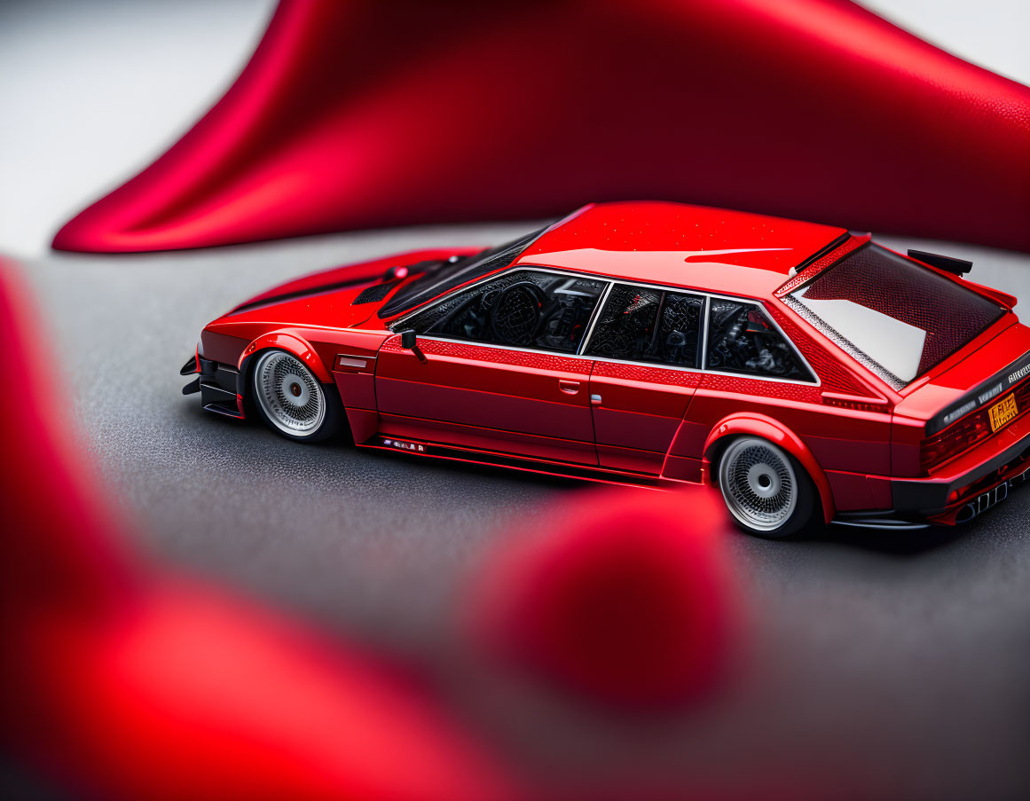 Vintage Red Sports Car Model Against Blurred Red Fabric Background