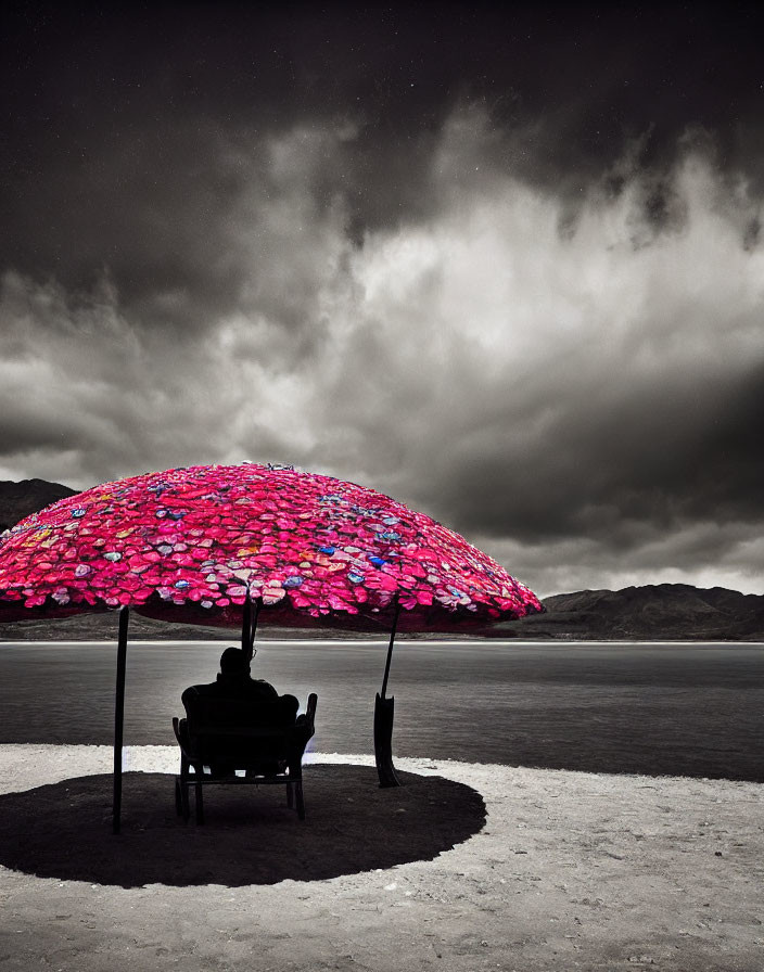 Vibrant pink umbrellas create shade over black table and chairs under stormy sky