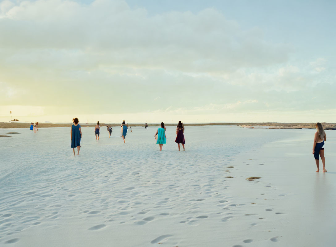 Beach scene: People walking towards the sea at dusk