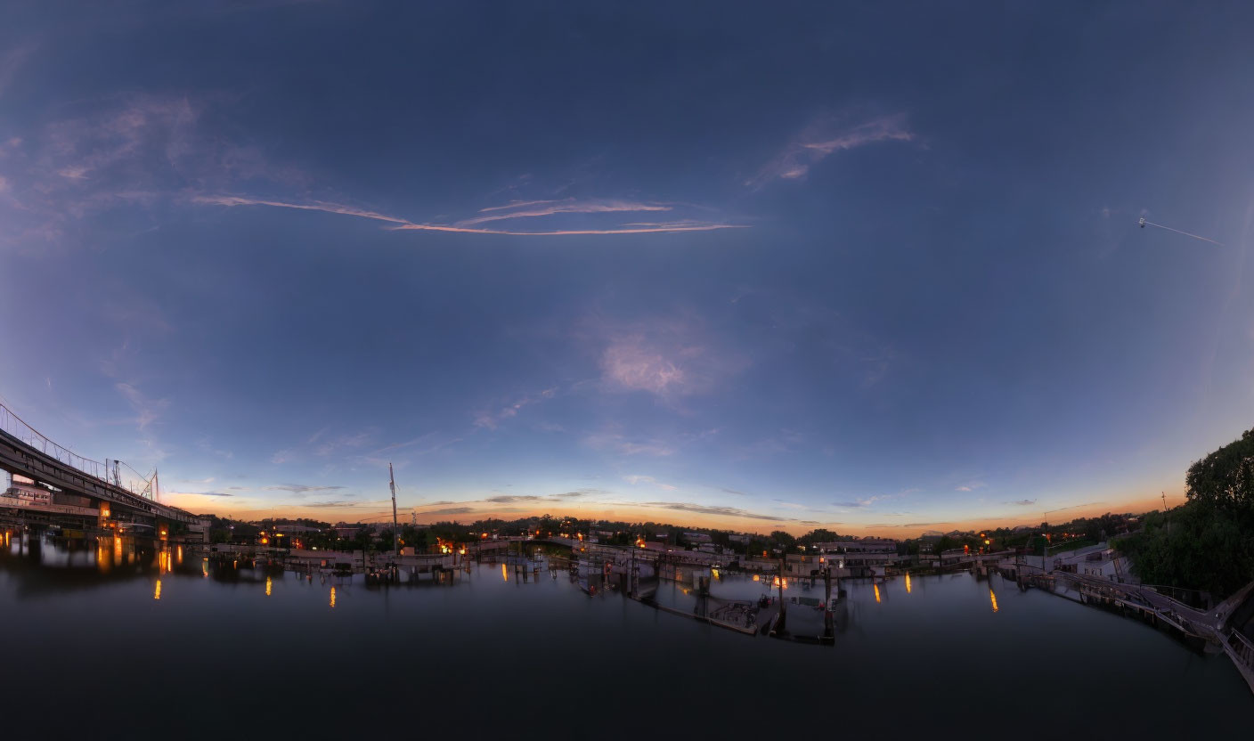 Twilight panoramic view of calm water with docks and cityscape reflections