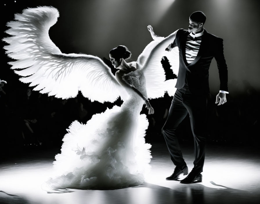 Two dancers in white and black outfits performing on stage under a spotlight