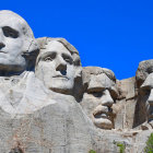 Sand sculpture of Mount Rushmore presidents under blue sky